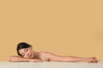 Beautiful young Asian woman with healthy skin on beige background