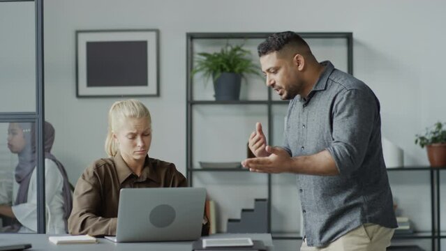 Medium shot of rude Middle Eastern man mistreating his Caucasian female subordinate at work in office
