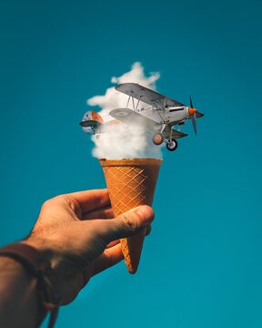 Graphic image of person holding ice-cream cone with cloud and airplane
