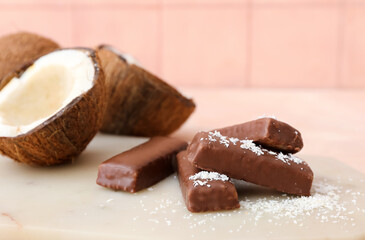 Board with tasty chocolate covered coconut candies on table