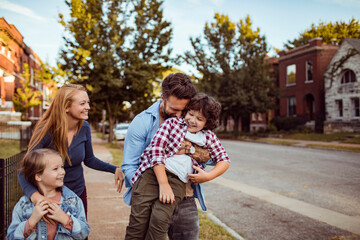 Young family walking on a sidewalk in a neighborhood of a city