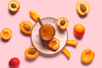 Jar with sweet apricot jam on pink background