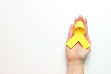 Yellow ribbon above a Woman’s hand in a white background and copy space in the left