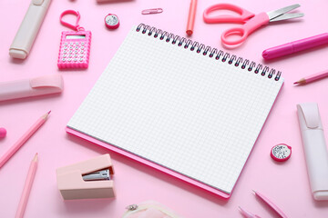 Notebook with different stationery supplies on pink background