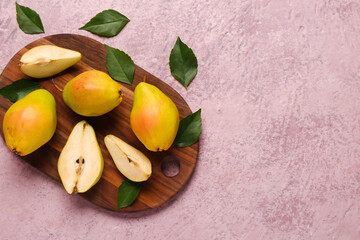 Wooden board with fresh pears and leaves on pink background