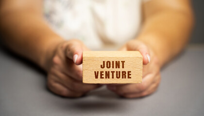 Joint venture on blocks concept. JV is a business entity created by two who parties shared returns...
