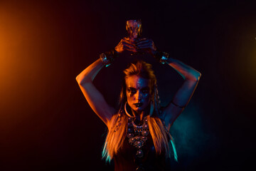 Fototapeta na wymiar Portrait of dangerous fearless valkyrie girl hold potion cup above head orange lights isolated on dark background