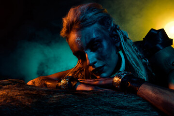 Portrait of frightening brave valkyrie girl blue orange lights mist animal fur isolated on dark background