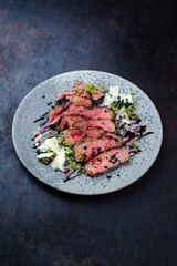 Italian tagliata de manzo roast beef steak slices with parmesan and capers served as close-up on a Nordic design plate with copy space