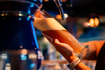 bartender woman hand at beer tap pouring a draught beer in glass serving in a restaurant or pub