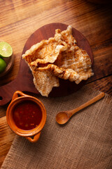 Chicharron. Crispy Fried pork rind, are pieces of aired and fried pork skin, traditional Mexican ingredient or snack served with lime juice and red hot sauce.