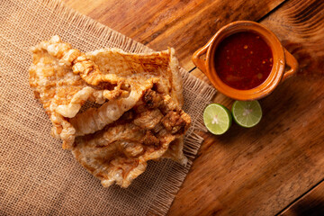 Chicharron. Crispy Fried pork rind, are pieces of aired and fried pork skin, traditional Mexican ingredient or snack served with lime juice and red hot sauce.