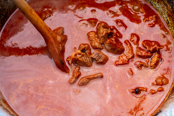 Traditional goulash soup is cooking in the a cauldron.