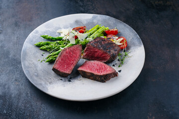 Italian barbecue dry aged chianina beef steak with green asparagus, cherry tomatoes and parmesan...