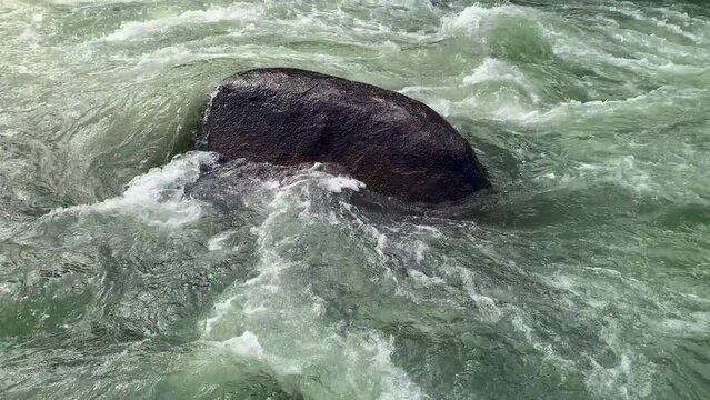 Rapidly flowing water around the beautiful boulder in the center of the picture