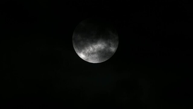 Full moon in the night through the clouds.