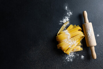 Fresh italian pasta with flour on dark background
