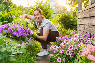 Gardening and agriculture concept. Young woman farm worker gardening flowers in garden. Gardener...
