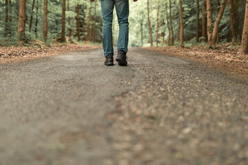 Man hiking walking on sunlit forest country road