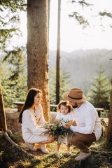 Happy family with flowers in sunny forest