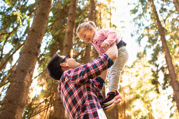 Carefree joyful father daughter bonding in having fun in sunlit forest showing happiness, love, togetherness