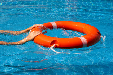 Lifeguard girl training with a life preserver swimming in the pool
