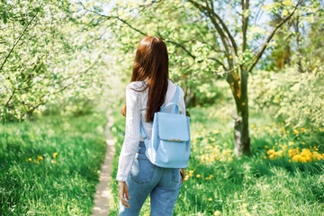 back view of european woman traveler happy relaxing outdoor under blue sky with sunlight. young girl backpacker walking in garden forest path way between forest tree and wood fence