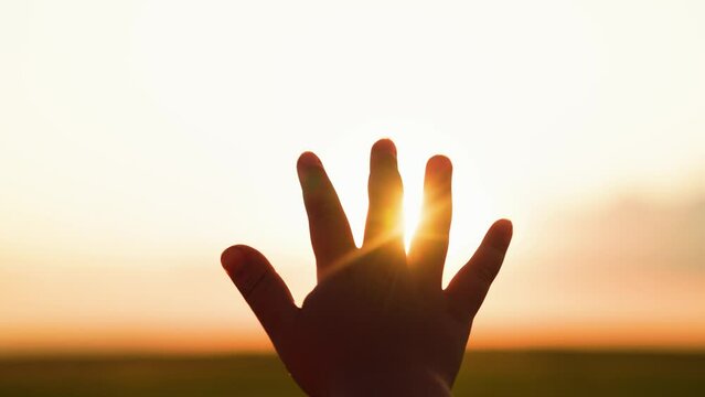 Little girl stretches his hand to sky, dreams in nature. Child is playing. Hand of child boy stretches to beautiful sky, sunset. Childrens dreams hopes, reach out your hands to sky. Childrens prayer