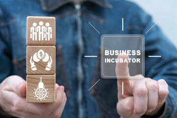 Man holding wooden cubes with icons clicks inscription on virtual screen: BUSINESS INCUBATOR. Concept of business incubator. Developing funding startup. Success investment. Business accelerator. - obrazy, fototapety, plakaty