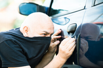Close up thief stealing car. Unlocked car, man trying to break into inside. The man dressed in...
