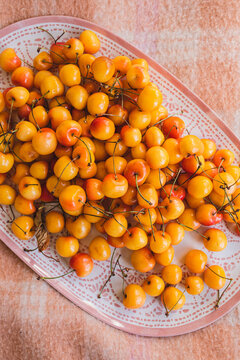 yellow Rainier cherries on tray, pink picnic blanket