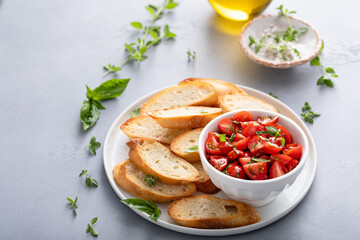 Making tomato basil bruschetta with toasted baguette and herbs