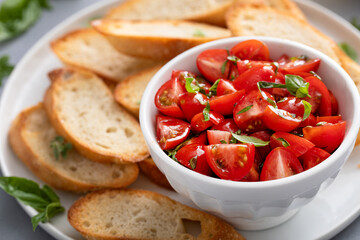 Making tomato basil bruschetta with toasted baguette and herbs