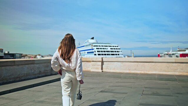 Tourist with a camera taking pictures of the cruise ship in Marseille. Beautiful girl enjoying the luxury yacht in France.
