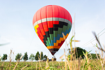 Open field with a large colorful hot air balloon being prepared for a trip through the skies. Photograph taken from a wide angle, from below