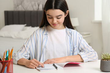 Teenage girl erasing mistake in her notebook at white desk indoors