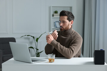 Man using long cigarette holder for smoking at workplace in office