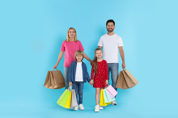 Family shopping. Happy parents and children with many colorful bags on light blue background