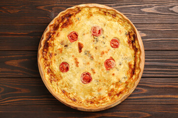 Delicious quiche with cheese and tomatoes on wooden table, top view