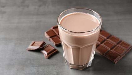 Glass of tasty chocolate milk on gray table. Dairy cacao drink