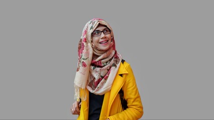 Close up portrait of smiling young Muslim woman wearing yellow jacket and brown hijab with red flower motif looking up. Happy and self confidence expression.