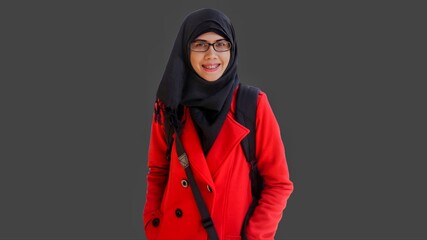 Close up portrait of smiling young Muslim woman wearing black hijab and red jacket. Happy and cheerful expression. 