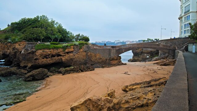 Basta Rock iconic bridge by Rocher de la Vierge in Biarritz town city, France. People tourists walk by a Beautiful rocky bridge on the seashore of the elegant royal town Biarritz.