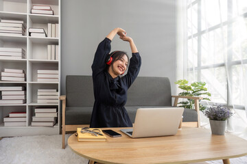 Cute asian woman listening to music happily on her laptop and enjoying listening to music at home.