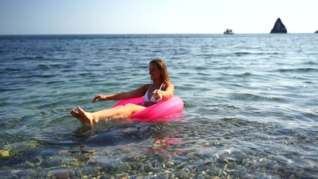 Summer vacation happy woman floats on an inflatable donut mattress, pink swim ring. Summer travel holidays vacation on the sea.
