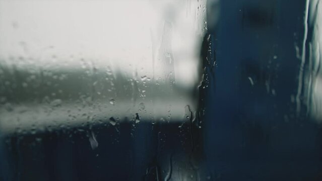 Close up of rain falling on a the window of a boat on a lake. Background is out of focus.