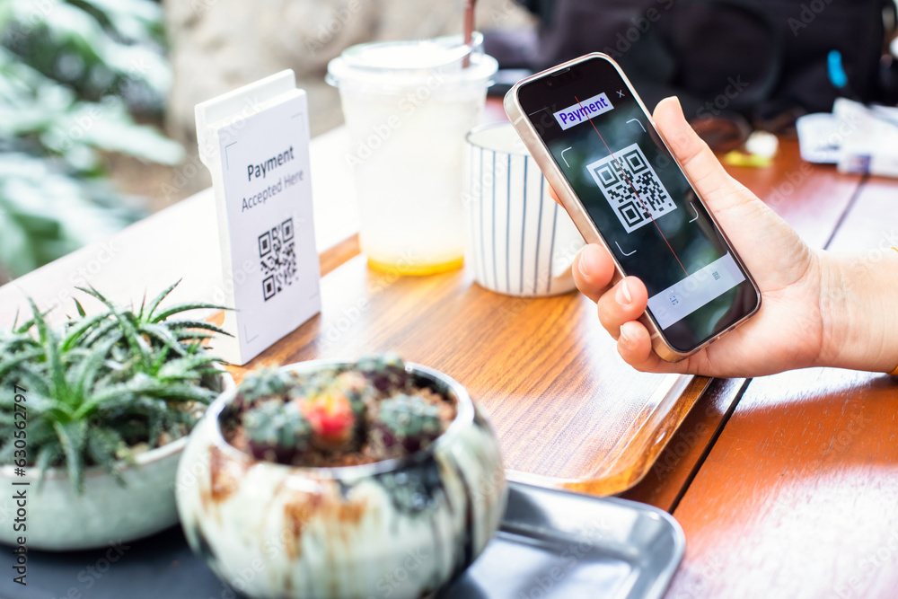 Wall mural customer hand using smart phone to scan qr code payment tag with blur coffee on wooden table to acce