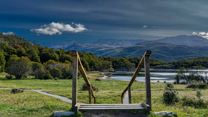 A wooden staircase with a railing descends to a green meadow. The paths are laid in the grass....