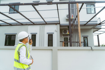 A house engineer checks the work on a village project through a tablet and takes a picture.
