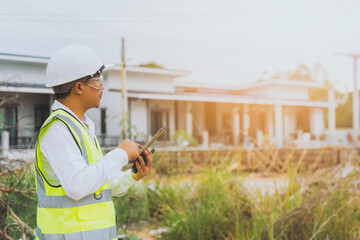 A house engineer checks the work on a village project through a tablet and takes a picture.